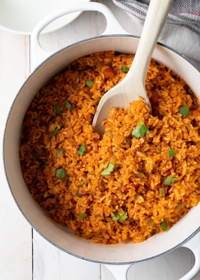 Spanish rice in a dutch oven with a wooden spoon. 