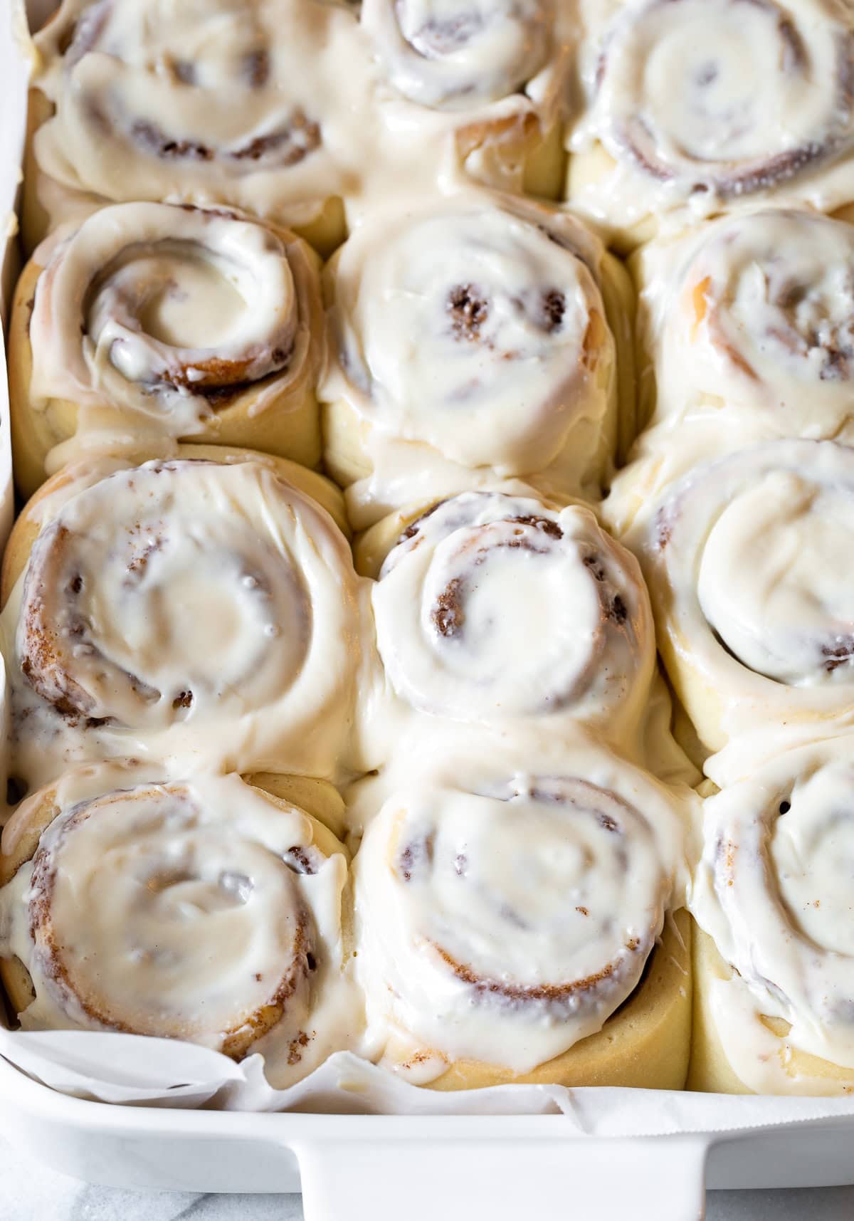 Overhead shot of cinnamon rolls in a pan with icing on top. 