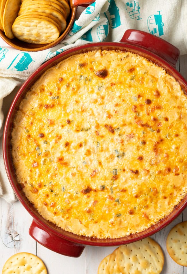 Overhead shot of hot cajun shrimp dip in a baking dish next to a bowl of crackers.