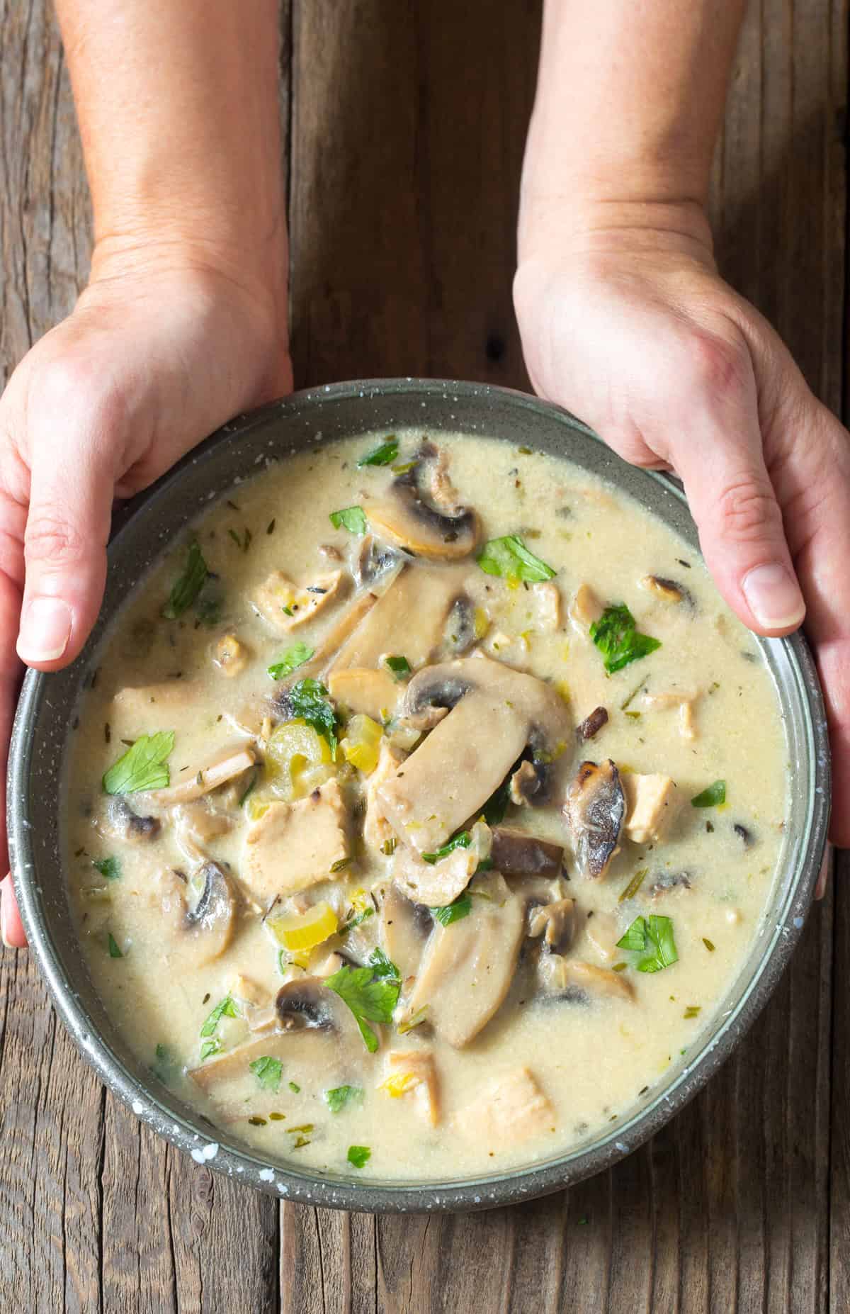 Creamy Chicken Mushroom Soup in bowl with hand holding the bowl