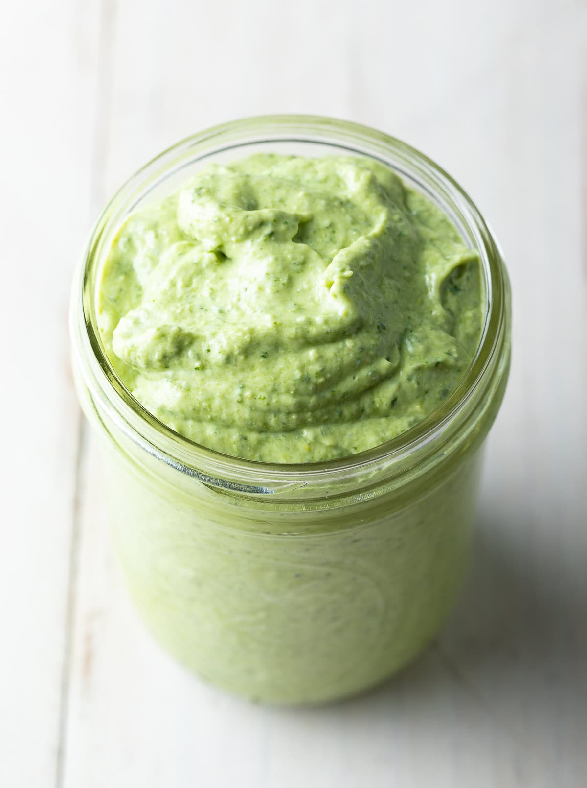 Close up of creamy pesto sauce in a jar. 