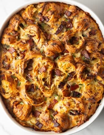 Overhead shot of croissant breakfast casserole recipe in a white baking dish, fresh from the oven.