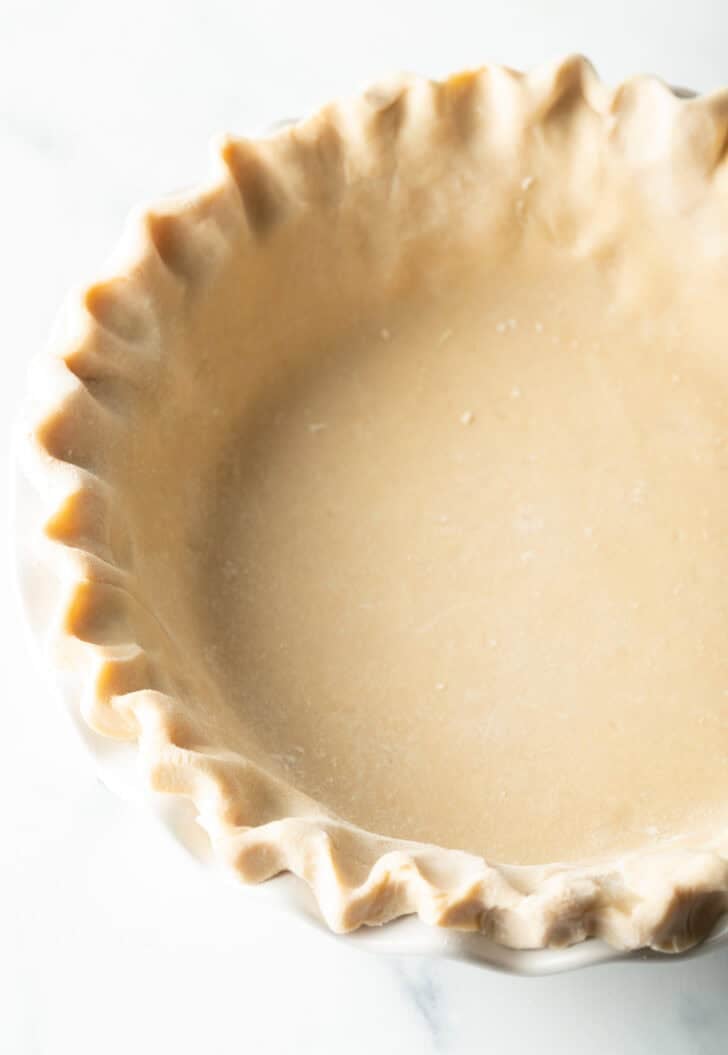 Unbaked pie dough with crimped edges in a pie plate.