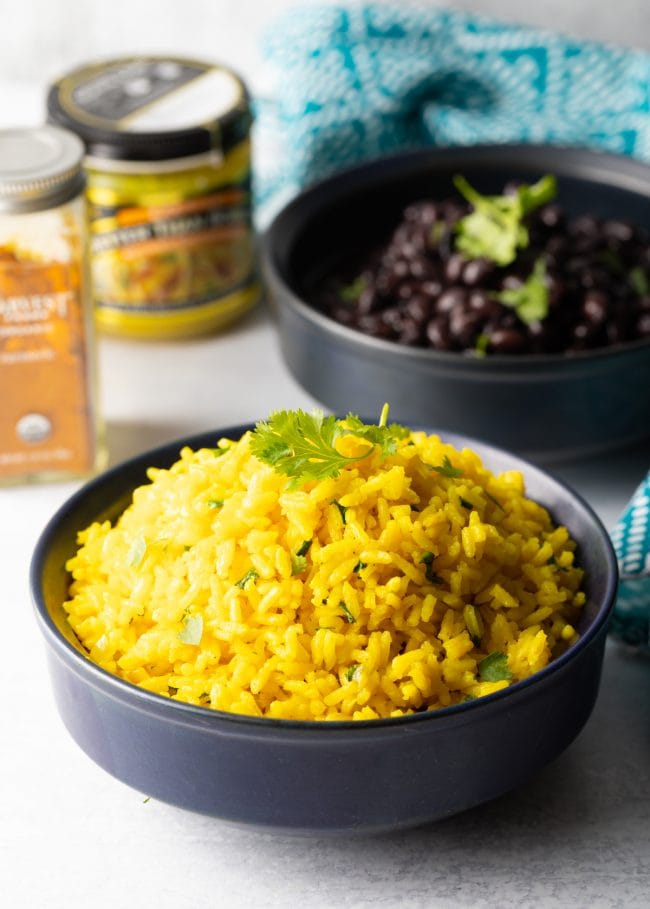 Closeup of yellow rice plated in bowl with cilantro garnish. 