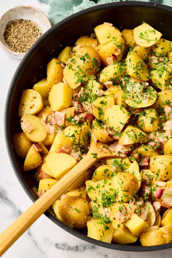 Hot German Potato Salad Recipe in pan with wooden spoon