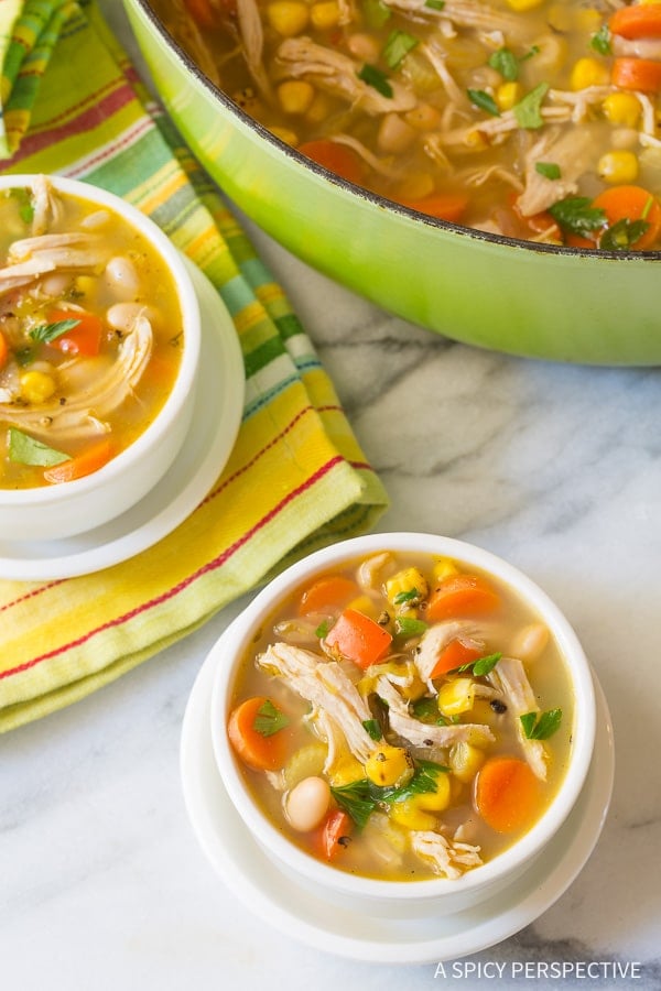 Chicken White Bean Soup in two white bowls with a green soup pot nearby.