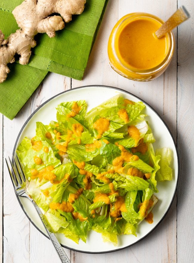 Overhead shot of romaine lettuce with drizzle of ginger salad dressing on top.