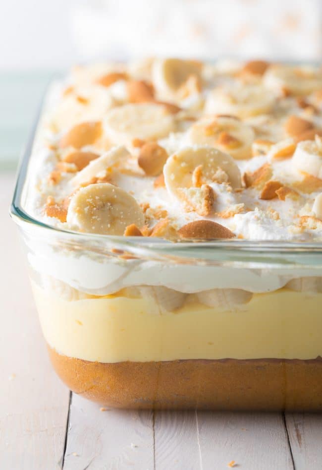 Banana pudding cake in a clear baking dish with layers showing on the side.