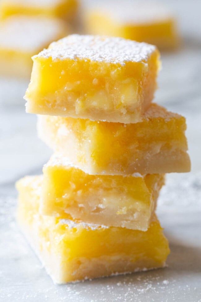 Lemon Bars #ASpicyPerspective #Lemon #Bars #LemonBars #LemonSquares #CookieCrust #WhiteChocolate #Spring #Dessert #Easter White Chocolate Lemon Bars Recipes - the best bars stacked on plate