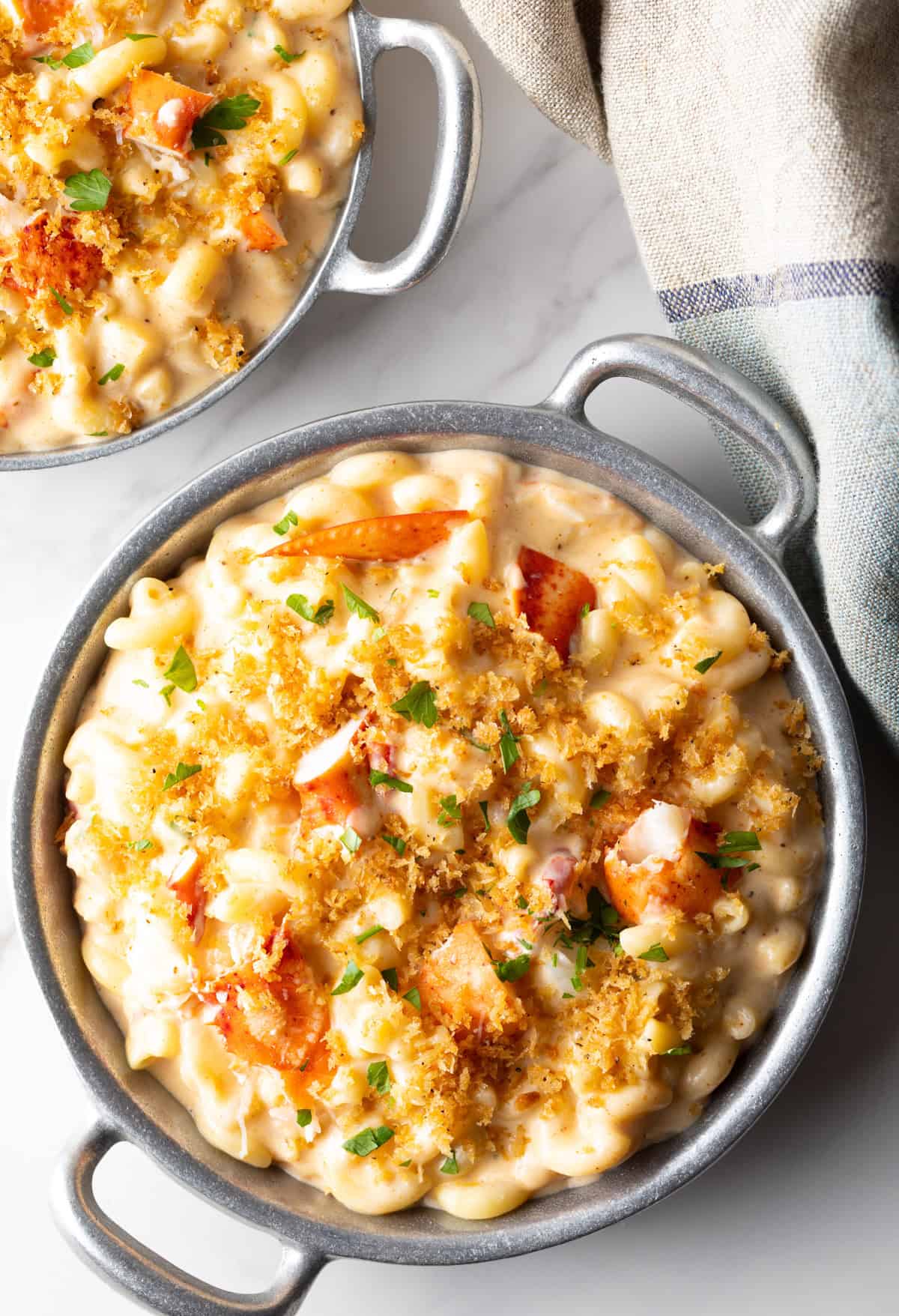 Two metal bowls filled with creamy lobster mac and cheese.