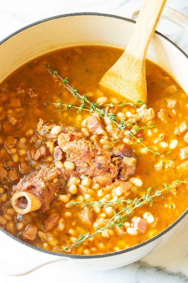 Ham and Bean Soup #ASpicyPerspective #HamAndBeanSoup #NavyBeans #HamAndBeans #NavyBeanSoup #BeanSoup #Soup Navy Bean Soup - Big pot full of soup with a wooden spoon
