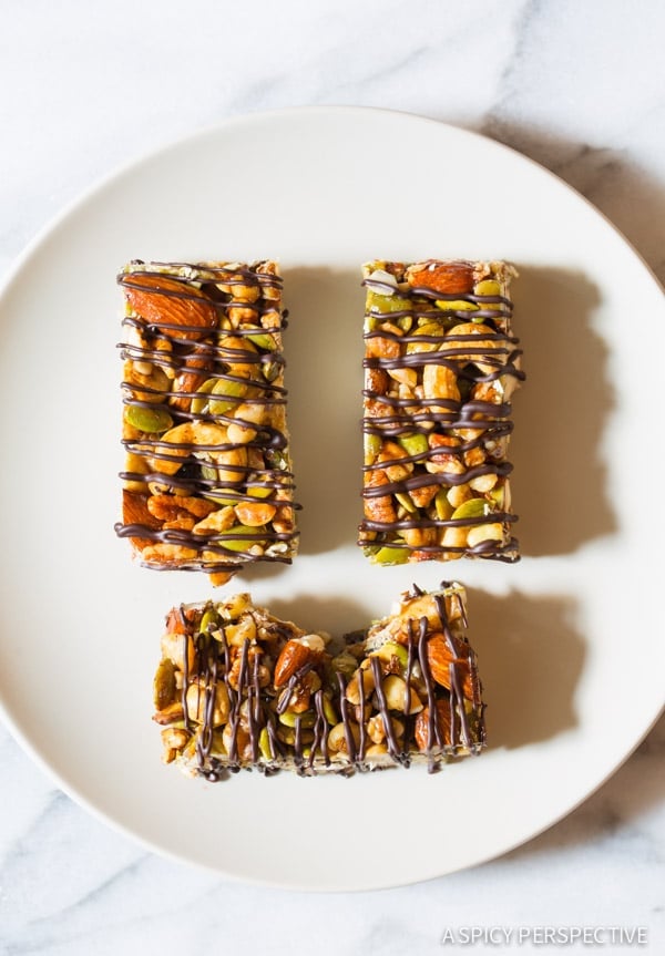 Top down view 3 paleo nut bars with chocolate drizzle on a white plate. 