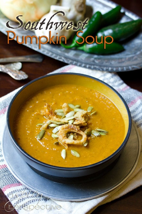 Blue bowl of pumpkin soup on a serving plate. 