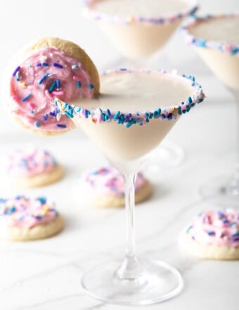 Colorful sugar cookie martini with a cookie on the rim surrounded by iced sugar cookies.