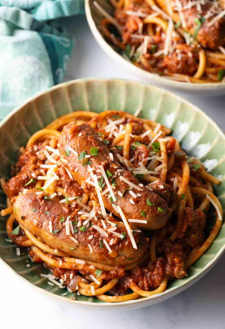 Green bowl with Sunday gravy pasta with meat sauce and sausages.