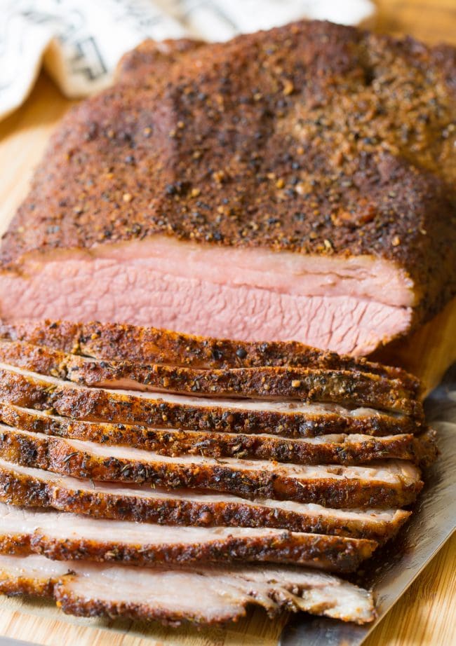 Oven Brisket on a cutting board with slices off the side. 